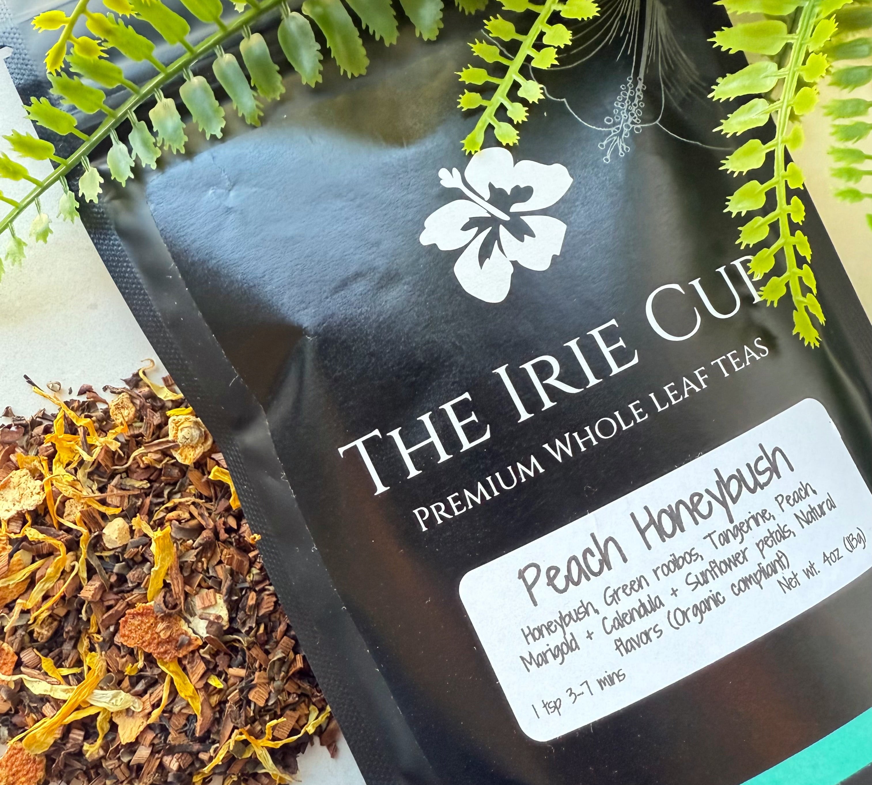 A package of 'The Irie Cup' Peach Honeybush tea with a visible label showing the product name and an image of the tea leaves surrounded by green foliage.