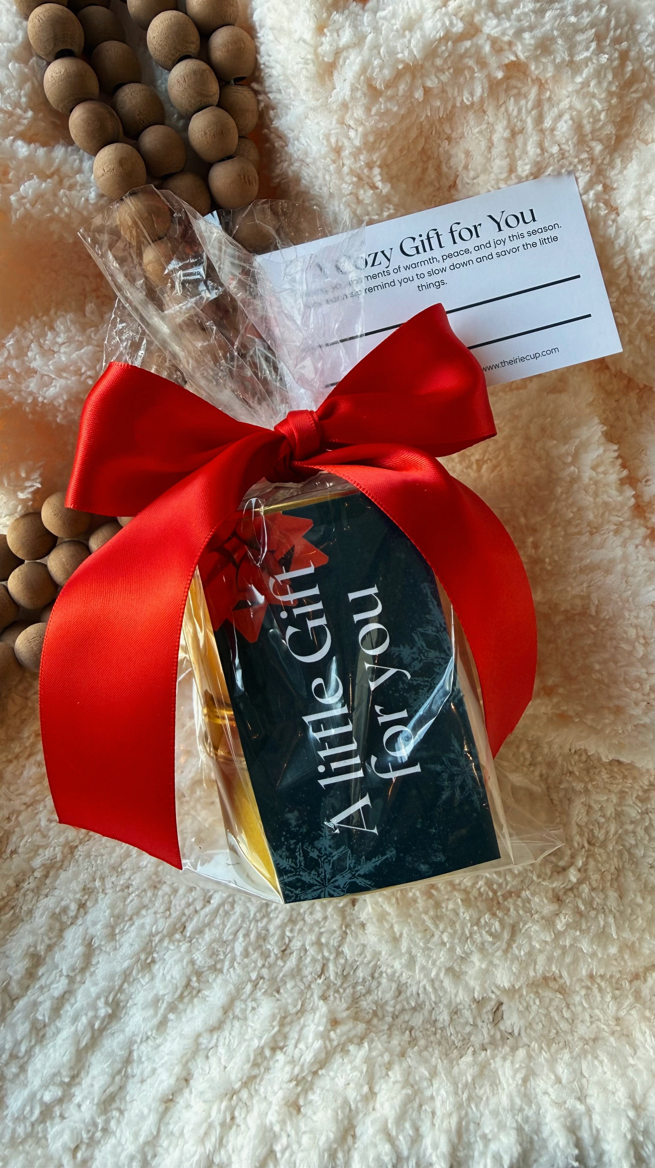 Gift bag with red ribbon and 'A Little Gift for You' tag on a textured surface