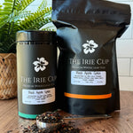 Tea packaging and loose tea on a wooden surface with a plant in the background
