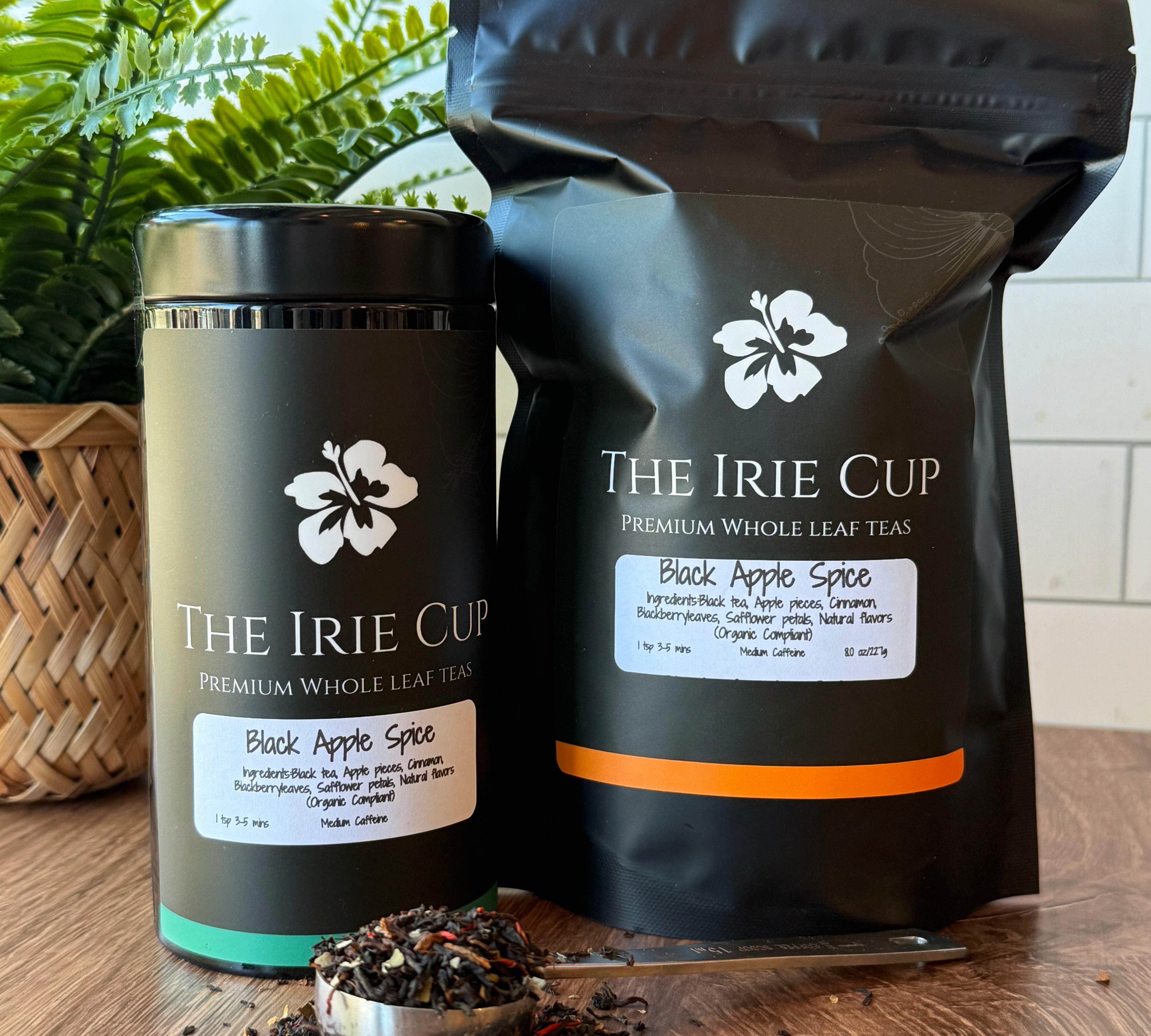 Tea packaging and loose tea on a wooden surface with a plant in the background