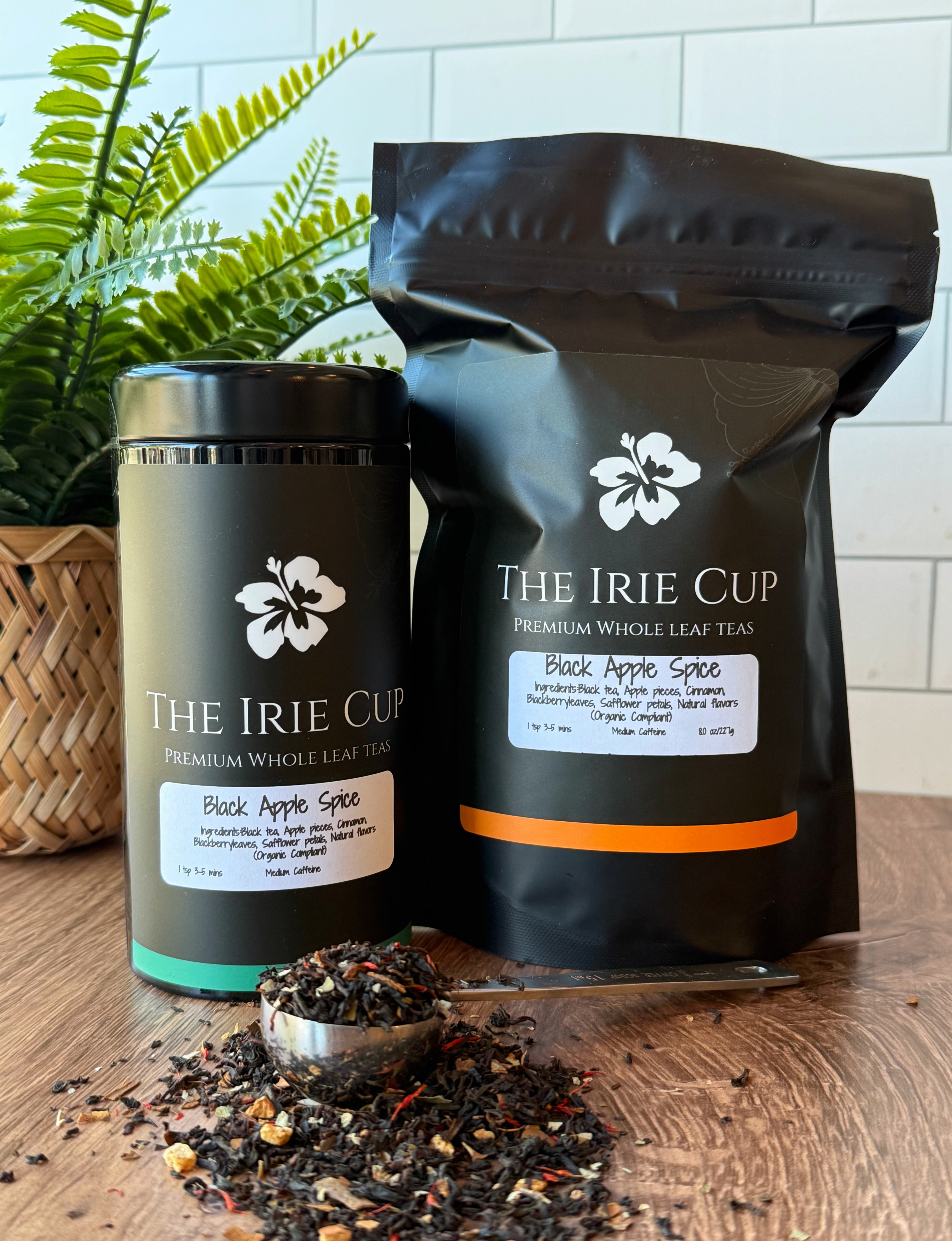 Tea packaging and loose tea on a wooden surface with a plant in the background