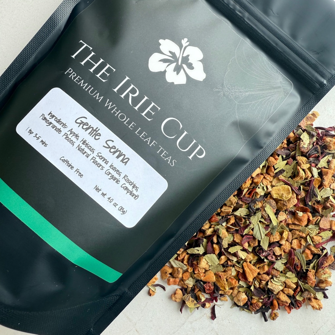 A package of Gentle Senna Herbal Tea by The Irie Cup with loose tea leaves, apple pieces, hibiscus, and rosehips scattered in front.