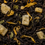 Close-up of black tea leaves with sugar cubes and herbs