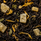 Close-up of black tea leaves with sugar cubes and herbs