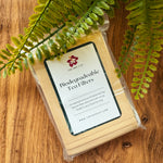 Biodegradable tea filters in a clear package on a wooden surface with fern leaves.