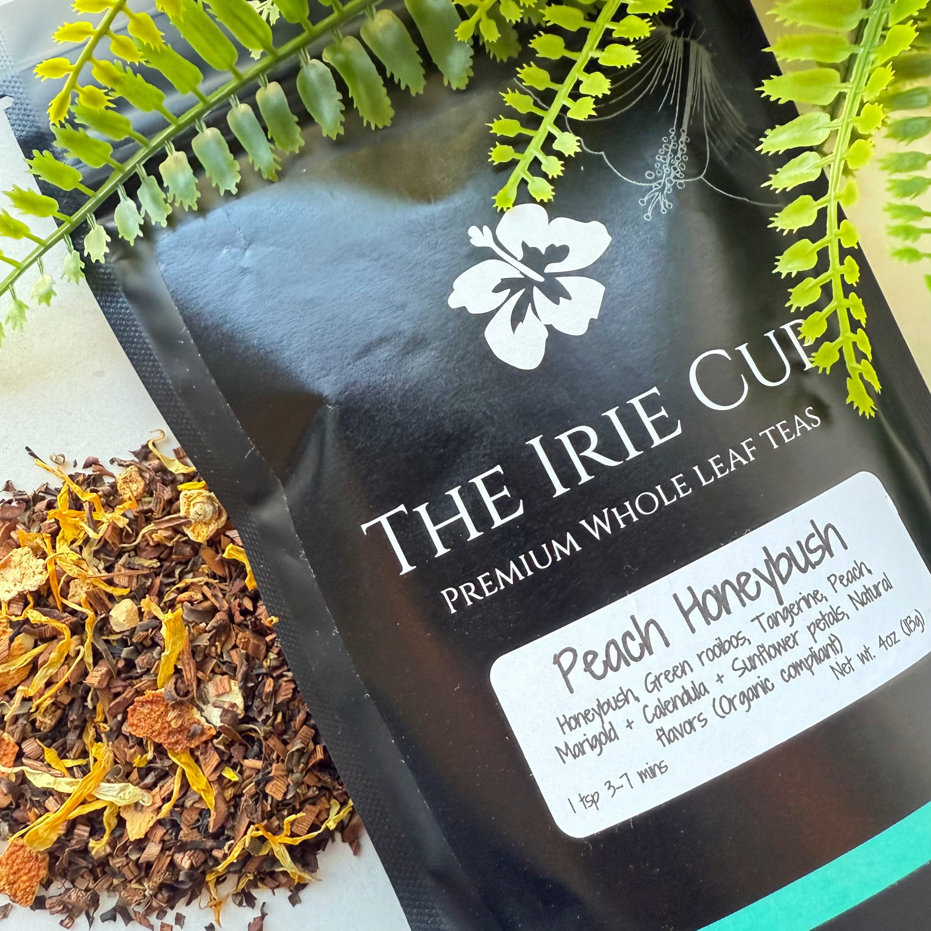 A package of 'The Irie Cup' Peach Honeybush tea with a visible label showing the product name and an image of the tea leaves surrounded by green foliage.