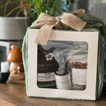 Gift set with 'The Irie Co.' products wrapped in green paper with a burlap bow on a wooden surface.