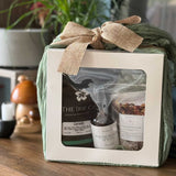 Gift set with 'The Irie Co.' products wrapped in green paper with a burlap bow on a wooden surface.