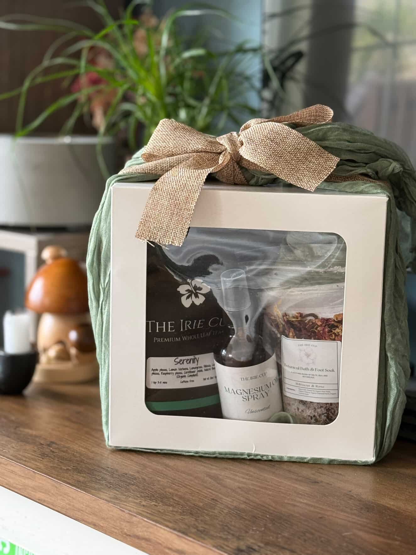 Gift set with 'The Irie Co.' products wrapped in green paper with a burlap bow on a wooden surface.