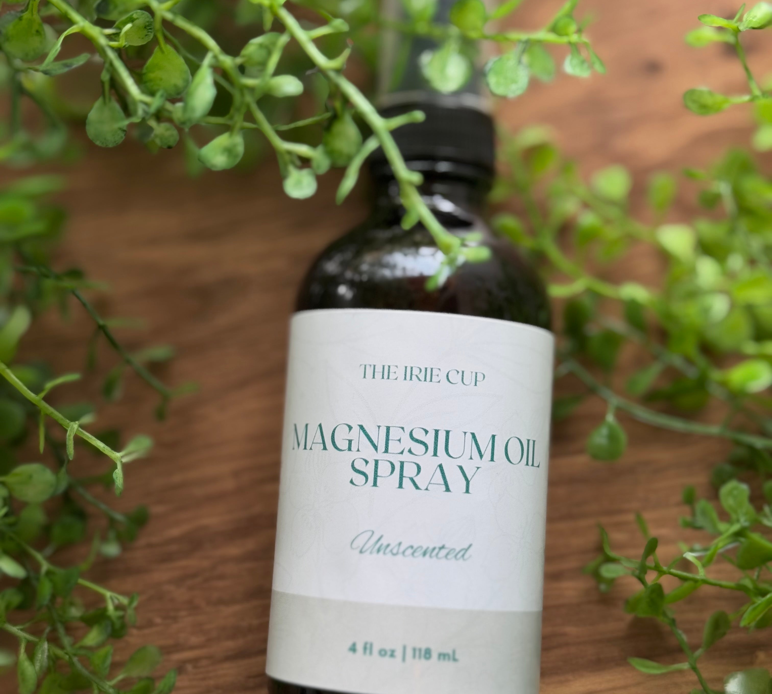 Three bottles of magnesium spray with labels in front of a green plant backdrop, two with spray nozzles visible and one with a dropper.