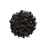 A close-up of dried tea leaves and pieces of blueberries, indicating a green tea blend with blueberry flavor.