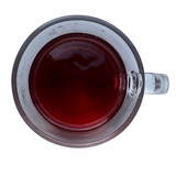 Bright pink iced herbal tea in a clear glass