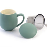 A teal porcelain mug with a stainless steel strainer and a matching porcelain lid, displayed against a white background.